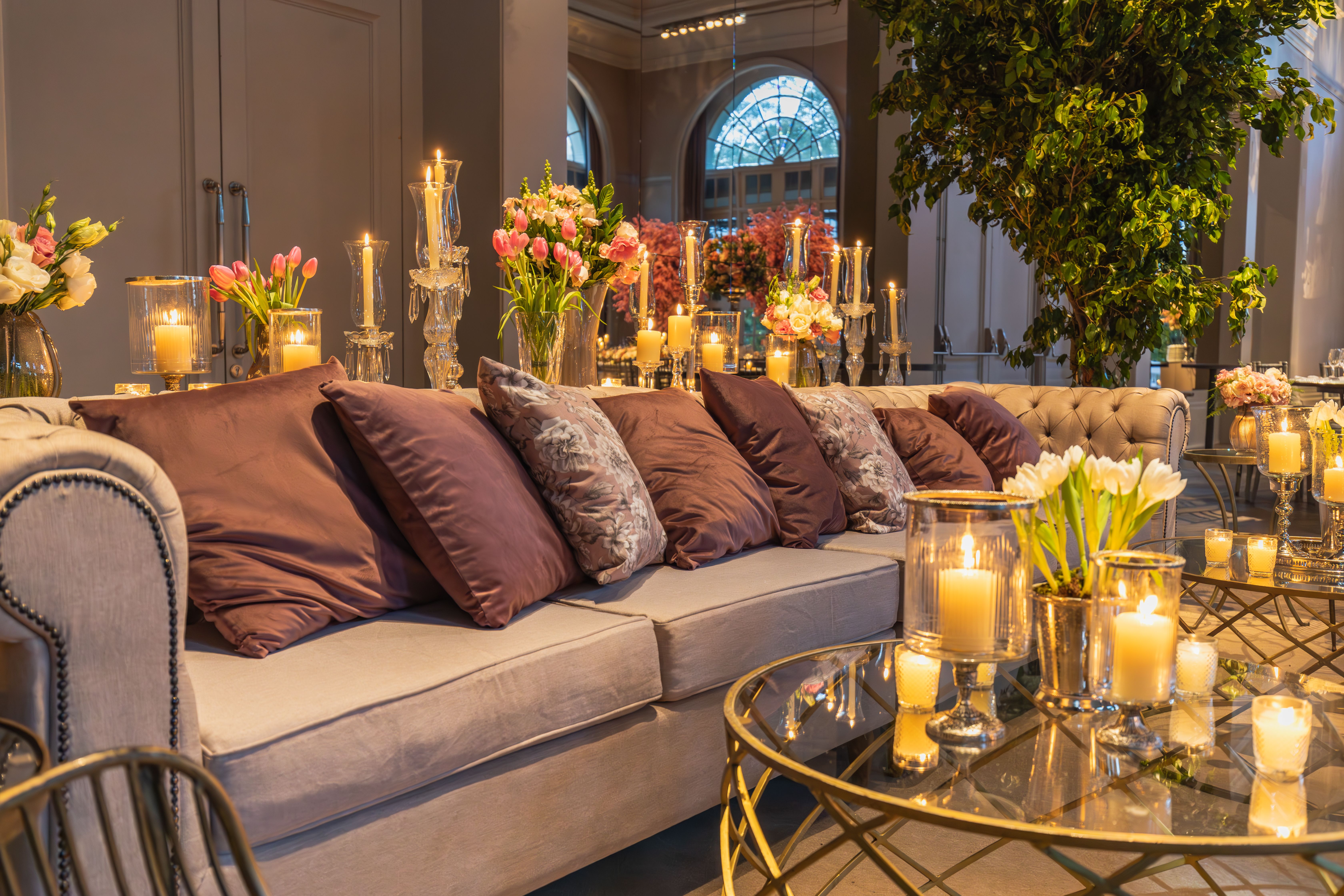 Intérieur élégant avec des bougies, des coussins et des décorations florales créant une atmosphère luxueuse.